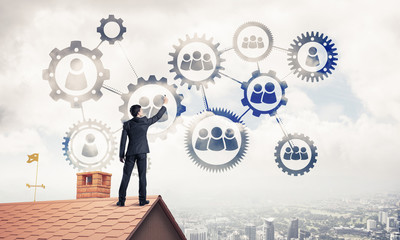 Businessman on house roof presenting teamwork and connection con