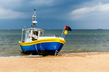 Naklejka na ściany i meble Fishing boat on the beach in Sopot, a major health-spa and tourist resort on the Polish Baltic Sea coast with the longest wooden pier in Europe at 515.5 meters.