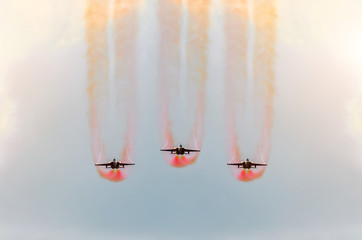Two fighter jets fly together with red smoke