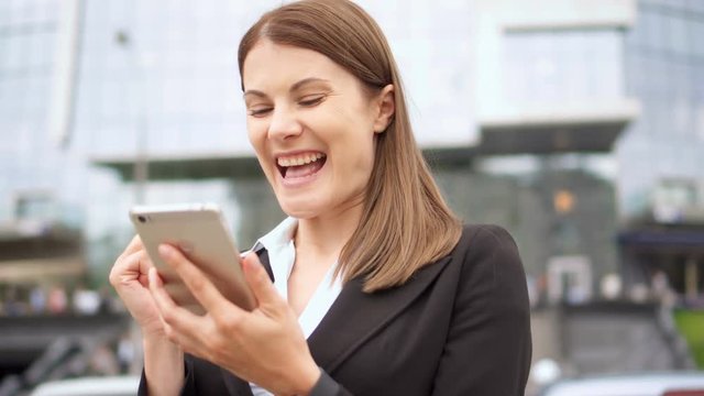 Businesswoman using smart phone in city downtown, professional female recieving good news excited