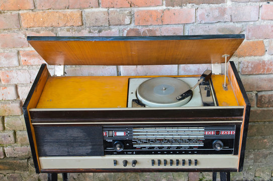 Old vintage antique radio with music record player on red brick wall background. .