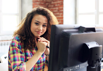 Beautiful business lady is looking at camera and smiling while working in office.