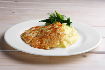 Plate with chopped pork in breading and mashed potato decorated with cucumber