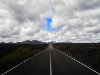 Empty endless highway through the volcanic landscape of Lanzarote island