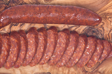 Guylai kolbasz, hungarian smoked sausage on natural olive wood cutting board