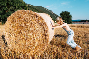 Girl in the field. Roll with hay. Slovenia. Sunset on the nature.