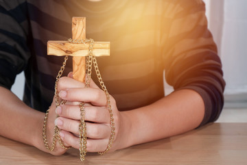 Woman hands holding wooden cross - religion concept