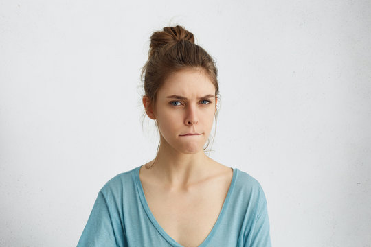 Serious angry woman frowning her face pressing lips togehter with anger trying to control herself and her emotions not showing her annoyance and anger. Dissatisfied young female in casual clothes