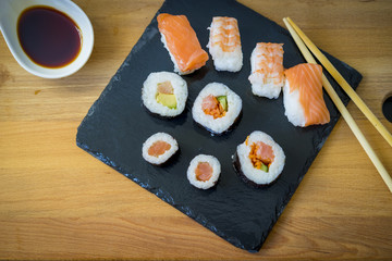 Asian dinner, Sushi on a wooden table on black slate plate with soy sauce and chopsticks
