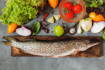 Fresh pike on the wooden boards with veetables and spices