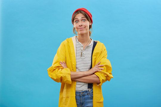Confused young female wearing casual clothes standing crossed hands isolated over blue background. Surprised woman looking with bugged eyes into camera sorting her relationships with husband