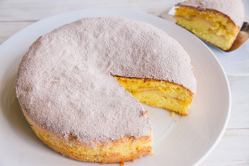 Homemade apple cake biscuit close up of a slice of cake on white plate on white wooden background 