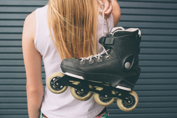 Pretty blonde girl posing with roller skates outdoors. Summer lifestyle portrait