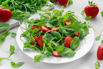 Fresh strawberry salad with arugula on white plate