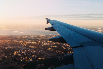 Airplane wing before landing in evening city