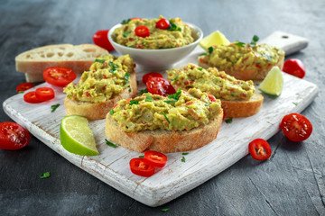 Homemade Guacamole toast with chili pepper, parsley on white wooden board