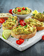 Homemade Guacamole toast with chili pepper, parsley on white wooden board