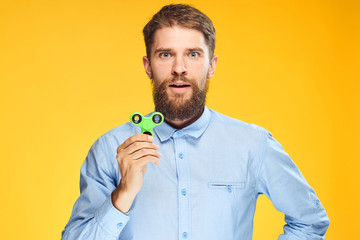 A young guy with a beard on a yellow background holds a spinner