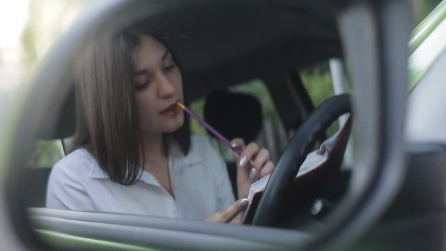 The girl driver communicates by phone in the parking lot and makes notes in her diary