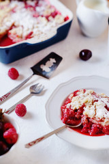 Delicious and juicy berry dessert, pie, coconut Crumble with strawberries, cherry, raspberries, black coffee and milk on a light background