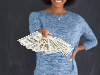 black woman holding money on gray background