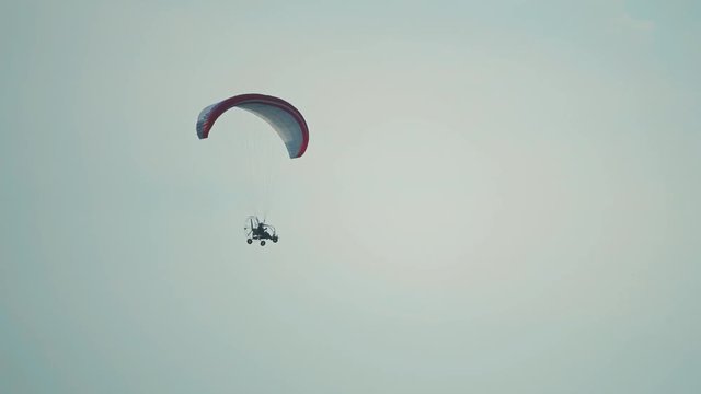 Unknown powered paraglider flying against blue sky