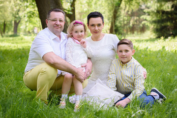 Fototapeta premium Grandfather with daughter, grandson and granddaughter in the park in the summer