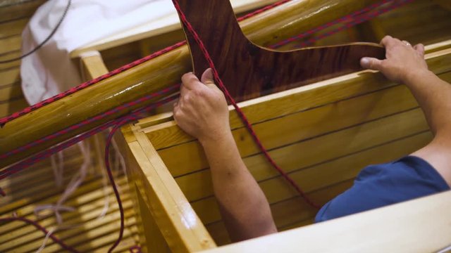 Mature master in glasses with assistant working with newly homemade wooden boat or sailboat in workroom. 4k. The last preparations before going to sea.