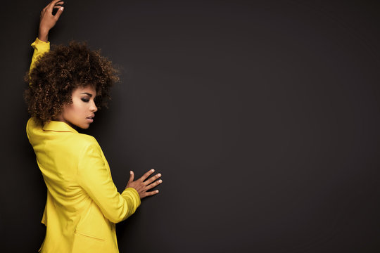 Girl with afro hairstyle posing in yellow jacket.