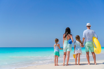 Back view of family of four on the beach. Family travel concept