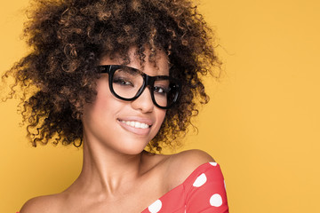 African american girl in eyeglasses on yellow background.