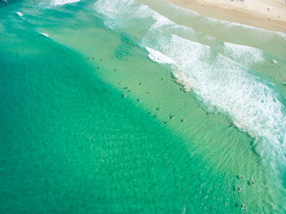 An aerial view of surfers waiting for a wave in the ocean on a clear day