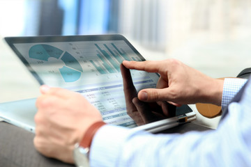 Business man working and analyzing financial figures on a graphs on a laptop outside