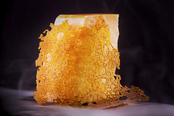 Cannabis oil concentrate aka shatter with cheese block isolated over black - medical marijuana...