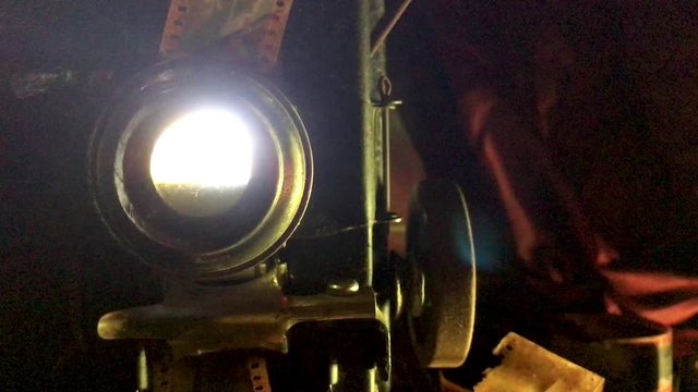 1920s Silent Film Projector with flashing light through lens in dark room
