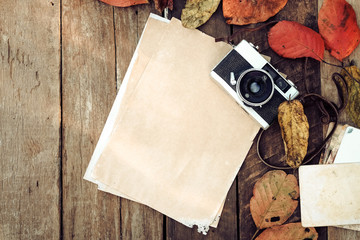 Retro camera and empty old instant paper photo album on wood table with maple leaves in autumn...