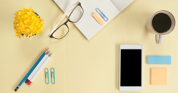 Female Desk Office With Notebook , Coffee Cup , Smart Phone, Notepad, Glasses, Pen And Flower On Yellow Background, Flay Lay And Copy Space For Texts