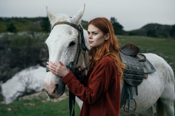 Beautiful young woman walking in the mountains with a horse