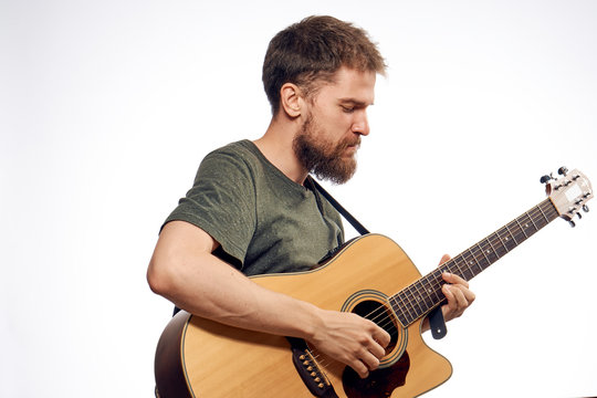 Young guy with a beard on a white isolated background holds a guitar