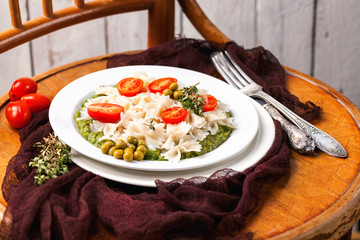 Paste with tomatoes and spinach sauce in a plate on an old chair. Style rustic. Italian food. Selective focus.