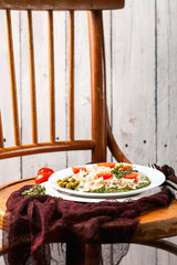 Paste with tomatoes and spinach sauce in a plate on an old chair. Style rustic. Italian food. Selective focus.