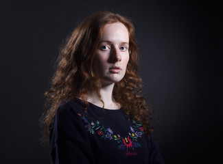 Fototapeta premium Portrait of young woman with red hair on a dark background.