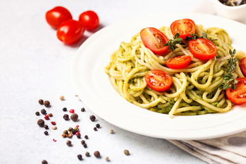 Paste with tomatoes and spinach sauce in a plate on a table. Selective focus. Copy space