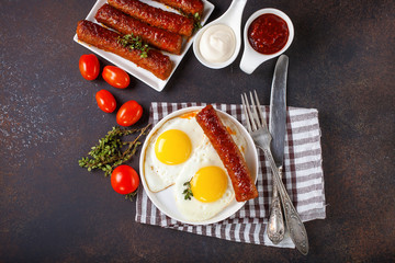 Breakfast - Fried eggs and meat sausages and sauces against a dark background. Selective focus. Copy space. Top view