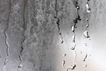 Detailed texture of water dripping down glass in a humid room. - obrazy, fototapety, plakaty