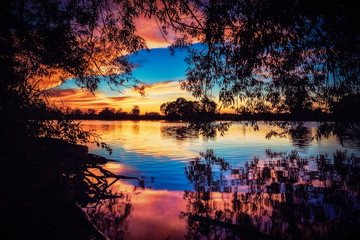 River Sunset Reflections. Tranquil Riverside Silhouette with Glowing Copy Space.