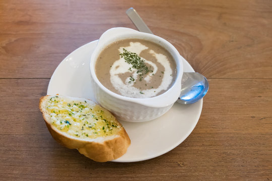 Mushroom cream soup in white bowl with garlic bread