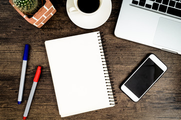 Brown wood office desk table with a book, pen, cactus and phone for working in top view and copy space.