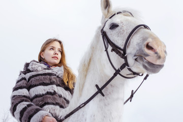 Nice girl and white horse outdoor in a winter