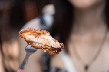 Woman has eating fried chicken with silver fork.